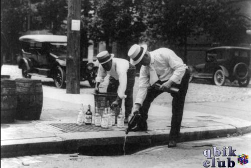 Двое мужчин выливают нелегальный алкоголь в канализацию во время Сухого закона